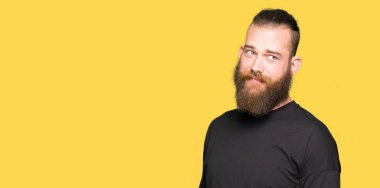 Rahat tişört giyen genç sarışın adam görünümlü bakan yan ve uzak düşünme bakıyor.