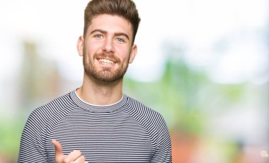 Hareketi el ile mutlu yaşasın yapıyor çizgili süveter giyen genç yakışıklı adam. Başarı gösteren kameraya bakarak ifade onaylama.