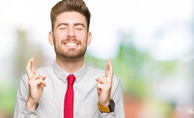 Umut ve gözleri kapalı geçiş parmaklarıyla gülümseyen genç yakışıklı iş adamı. Şans ve batıl kavramı.