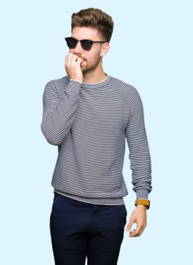 Genç yakışıklı adam stresli ve gergin ile eller tırnak ısırma dudaklarından seyir güneş gözlüğü takıyor. Anksiyete sorunu.