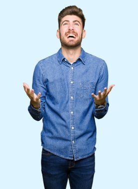 Casual kot gömlek çılgın ve kızgın bağırarak ve agresif ifade ve silah kaldırdı bağırmaya giyen genç yakışıklı sarışın adam. Hayal kırıklığı kavramı.