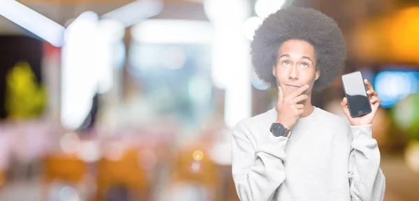 スマート フォン画面深刻な顔を考えて質問 非常に混乱した考えを示すアフロの髪の若いアフリカ系アメリカ人 — ストック写真
