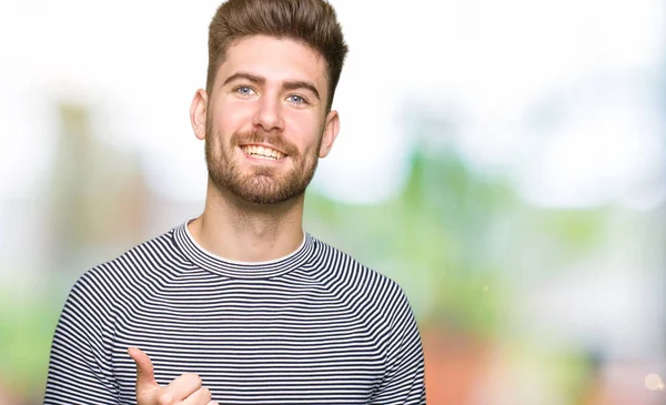 Hareketi el ile mutlu yaşasın yapıyor çizgili süveter giyen genç yakışıklı adam. Başarı gösteren kameraya bakarak ifade onaylama.