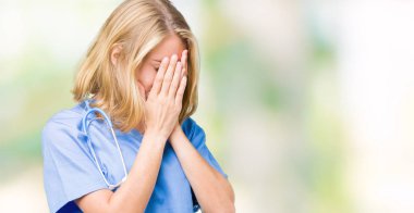Yüzünü elleriyle ağlayarak süre kapsayan üzgün ifade ile izole arka plan üzerinde tıbbi üniforma giyen güzel genç doktor kadın. Depresyon kavramı.