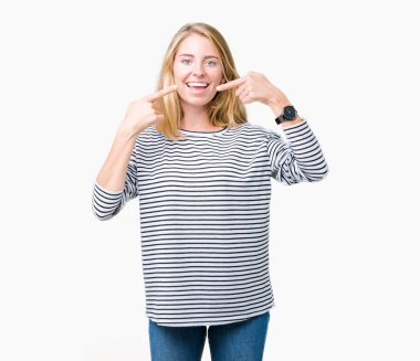 Kendinden emin gösterilen ve işaret parmakları diş ve ağız ile gülümseyen izole arka plan üzerinde çizgili süveter giyen güzel genç kadın. Sağlık kavramı.