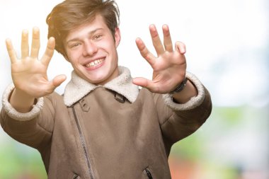 Gösterilen arka plan üzerinde kış ceket giyen genç yakışıklı adam izole ve parmakları ile işaret numara 9 kendinden emin ve mutlu gülümseyerek süre.