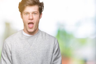 İzole arka plan korkuyor ve şok sürpriz ifade, korku ve heyecan yüz üzerinden sweatshirt giyen genç yakışıklı sportif adam.