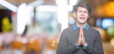 İzole arka plan üzerinde genç yakışıklı zarif adam yalvarıyor ve yüz üzerinde umut ifade ile birlikte eller ile dua çok duygusal ve endişeli. Affedilmesini istiyorum. Din konsepti.