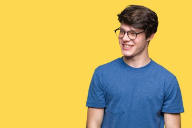 Uzak tarafına yüzünde, doğal ifade gülümseme ile seyir izole arka plan üzerinde gözlük takan yakışıklı delikanlı. Kendine güvenen gülüyor.