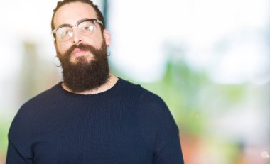 Genç hipster adam uzun saçlı ve gözlüklü eller birlikte sakal ve parmakları ile rahat ve neşeli gülümseyen geçti. Başarı ve iyimser