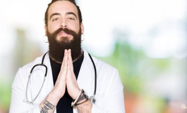 Doktor uzun saçlı tıbbi ceket ve elle AF emin gülümseyen için soran birlikte dua stetoskop.