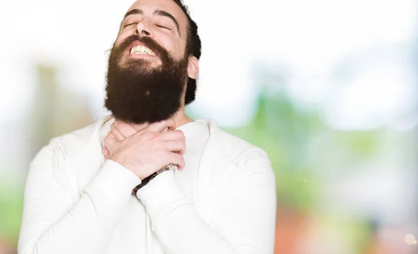 Young man with long hair and beard wearing sporty sweatshirt shouting and suffocate because painful strangle. Health problem. Asphyxiate and suicide concept.