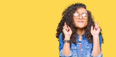 Genç güzel kadın kıvırcık saçlı giyen ile gülümseyen geçiş parmakları ile umut ve gözleri kapalı gözlükler. Şans ve batıl kavramı.