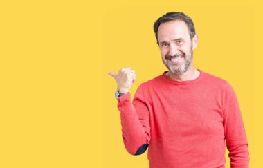 Mutlu yüz görünümlü ve başparmak yukarı ile yan işaret ile gülümseyen izole arka plan üzerinde kış kazak giyen yakışıklı Orta Çağ ağarmış kıdemli adam.