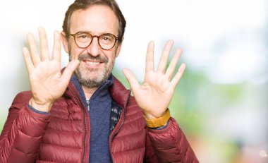 Gözlük ve gösterilen ve parmakları ile işaret kış ceket giyen orta yaş yakışıklı adam kendinden emin ve mutlu gülümseyerek süre on numara.