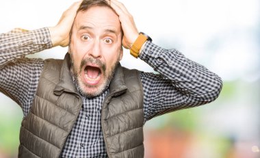 Kış yeleği deli ve baş, korkuyor ve açık ağzı ile şok sürpriz elleriyle korkuttu orta yaş yakışıklı adam