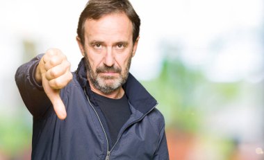 Orta yaş yakışıklı adam mutsuz ve kızgın ret gösterilen ve başparmak aşağı hareketi ile negatif seyir bir ceket giyiyor. Kötü ifade.