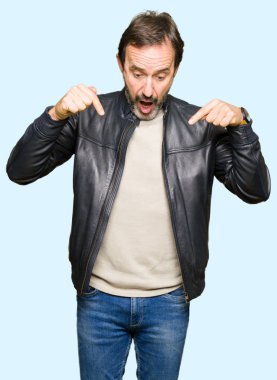 Siyah deri giyen orta yaş yakışıklı adam aşağı reklam, sürpriz yüz ve açık ağız gösterilen parmakları ile işaret ceket