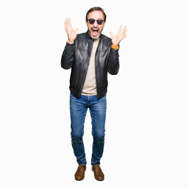 Orta yaş yakışıklı adam güneş gözlüğü giyiyor ve siyah deri ceket çılgın kutluyor ve başarı için hayran silah kaldırdı ve açık gözleri heyecanlı çığlık. Kazanan kavramı