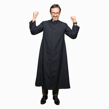 Orta yaş rahip adam gurur gülümseyen silah kasları gösteren Katolik Robe giyiyor. Fitness konsepti.