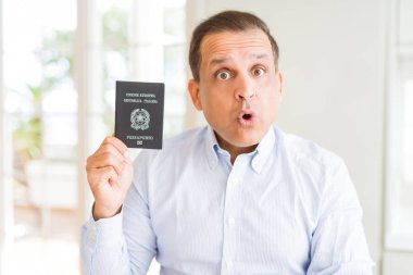 İtalya pasaportu tutan orta yaşlı adam sürpriz bir yüzle şokta korkmuş, korku yla korkmuş ve heyecanlı ifade