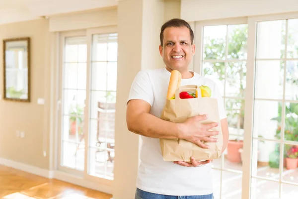 Orta yaş erkek holding grocieries evde sebze dolu çanta — Stok fotoğraf