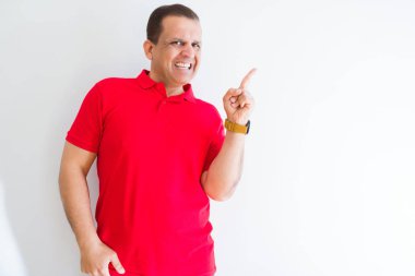 Yüzünde büyük bir gülümseme ile beyaz duvar üzerinde kırmızı t-shirt giyen orta yaş adam, kamera bakarak yan el ve parmak ile işaret.