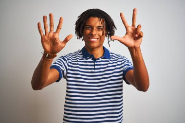 Çizgili mavi polo giyen dreadlocks giyen Afro adam izole beyaz arka plan üzerinde duran gösteren ve parmakları ile işaret ederken emin ve mutlu gülümseyerek sekiz.