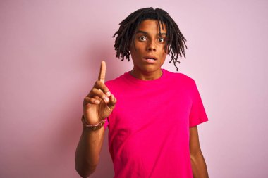 Afro amerikan adam dreadlocks giyen t-shirt izole pembe arka plan üzerinde başarılı bir fikir ile parmak işaret ayakta. Çıktı ve mutlu. Bir numara.
