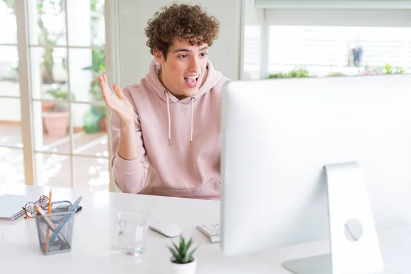 Young student man using computer very happy and excited, winner expression celebrating victory screaming with big smile and raised hands