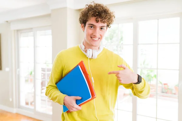 年轻的学生男子戴着耳机 拿着笔记本 带着惊讶的脸指着自己 — 图库照片