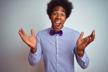 İzole beyaz arka plan üzerinde çizgili gömlek ve mor yay kravat giyen Afro iş adam deli kutluyor ve başarı için hayran silah kaldırdı ve açık gözleri heyecanlı çığlık. Kazanan kavramı
