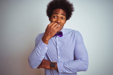İzole beyaz arka plan üzerinde çizgili gömlek ve mor yay kravat giyen Afro iş adamı vurguladı ve ağız ısırma çivi elleri ile sinir bakıyor. Anksiyete sorunu.
