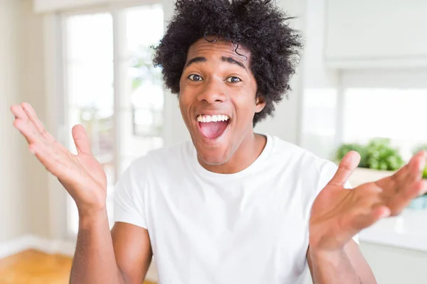 アフリカ系アメリカ人の男性は クレイジーを祝う白いTシャツを着て 腕を上げて目を開けて興奮して成功に驚きました 勝者のコンセプト — ストック写真