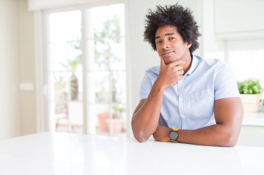 Afro-Amerikan iş adamı çapraz kolları ve çene üzerinde kaldırdı el ile gülümseme ile kameraya emin bakıyor. Olumlu düşünme.