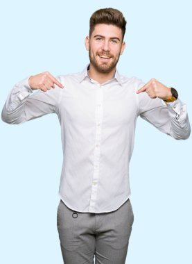 Yüzünde gülümseme ile kendinden emin görünüyorsun, kendini gururlu ve mutlu parmakları ile işaret genç yakışıklı iş adamı.