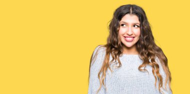 Görünümlü yan ve dik dik bakma uzağa düşünce gülümseyen kış kazak giyen genç güzel kadın.