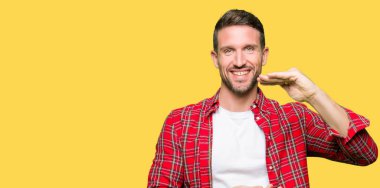 Yakışıklı adam, büyük ve büyük boyutlu işareti gösteren elleri ile işaret rahat gömlek giyiyor, ölçmek sembolü. Kameraya bakarak gülümsüyor. Ölçme konsepti.