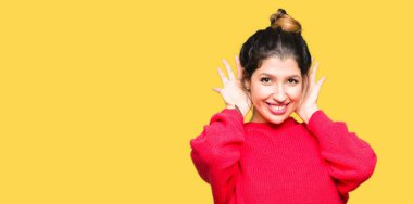 Kırmızı kazak ve iki eliyle kulak jest, dedikodu için meraklı üzerinde dinliyoruz topuz giyen genç güzel kadın. İşitme sorunu, sağır