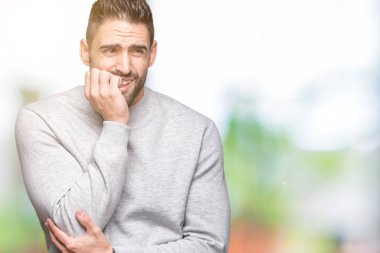 Genç yakışıklı adam stresli ve gergin ile izole arka plan üzerinde sweatshirt giyen tırnak ısırma dudaklarından eller. Anksiyete sorunu.