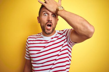 Sarı izole arka plan üzerinde rahat kırmızı çizgili t-shirt giyen genç yakışıklı adam hata için baş el ile şaşırdı, hatayı hatırlıyorum. Unuttum, kötü bellek kavramı.