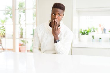 Beyaz masada yakışıklı afro-amerikan adam el ile ağız kapsayan yorgun esneme sıkılmış. Huzursuz ve uykululuk.