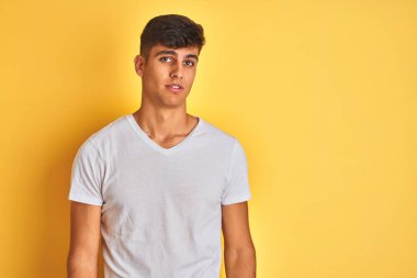 Genç hintli adam izole sarı arka plan üzerinde ayakta giyen uykulu ve yorgun görünümlü, yorgunluk ve akşamdan kalma için yorgun, sabah tembel gözleri.