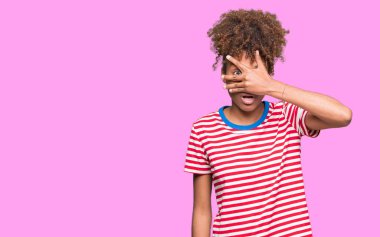 Yüz ve gözler el ile kapsayan şok bakmak izole arka plan üzerinde güzel genç Afro-Amerikan kadın mahcup ifadeyle parmaklarımın arasından arıyorsunuz.