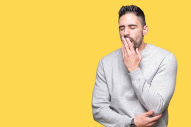 Genç yakışıklı adam kazak giyiyor izole arka plan üzerinde el ile ağız kapsayan yorgun esneme sıkılmış. Restless ve uyku hali.