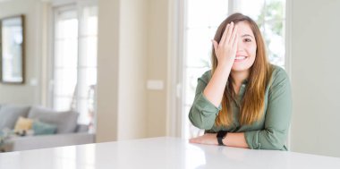 Güzel genç kadın yüzünde kendine güvenen gülümseme ve sürpriz duygu ile bir göz ile bir göz kapsayan evde.