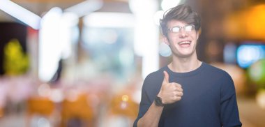 Hareketi el ile mutlu yaşasın yapıyor izole arka plan üzerinde gözlük takan yakışıklı delikanlı. Başarı gösteren kameraya bakarak ifade onaylama.