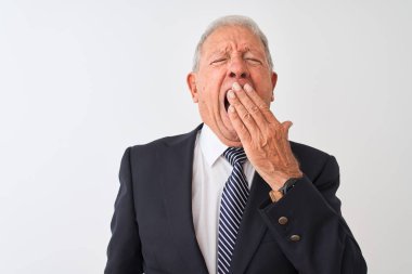 Üst düzey gri saçlı işadamı izole beyaz arka plan üzerinde duran takım elbise giyen el ile ağız kapsayan yorgun esneme sıkılmış. Huzursuz ve uykululuk.