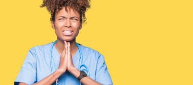 Genç Afro-Amerikan doktor kadın dilencilik ve umut ifade yüzünde çok duygusal ve endişe ile birlikte elleriyle dua izole arka plan yüzünden. Bağışlanmak. Din kavramı.