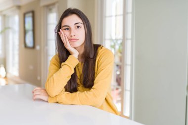 Güzel genç kadın sarı kazak yorgun görünümlü ve çarpılan silah ile depresyon sorunları ile sıkılmış düşünme giyiyor.